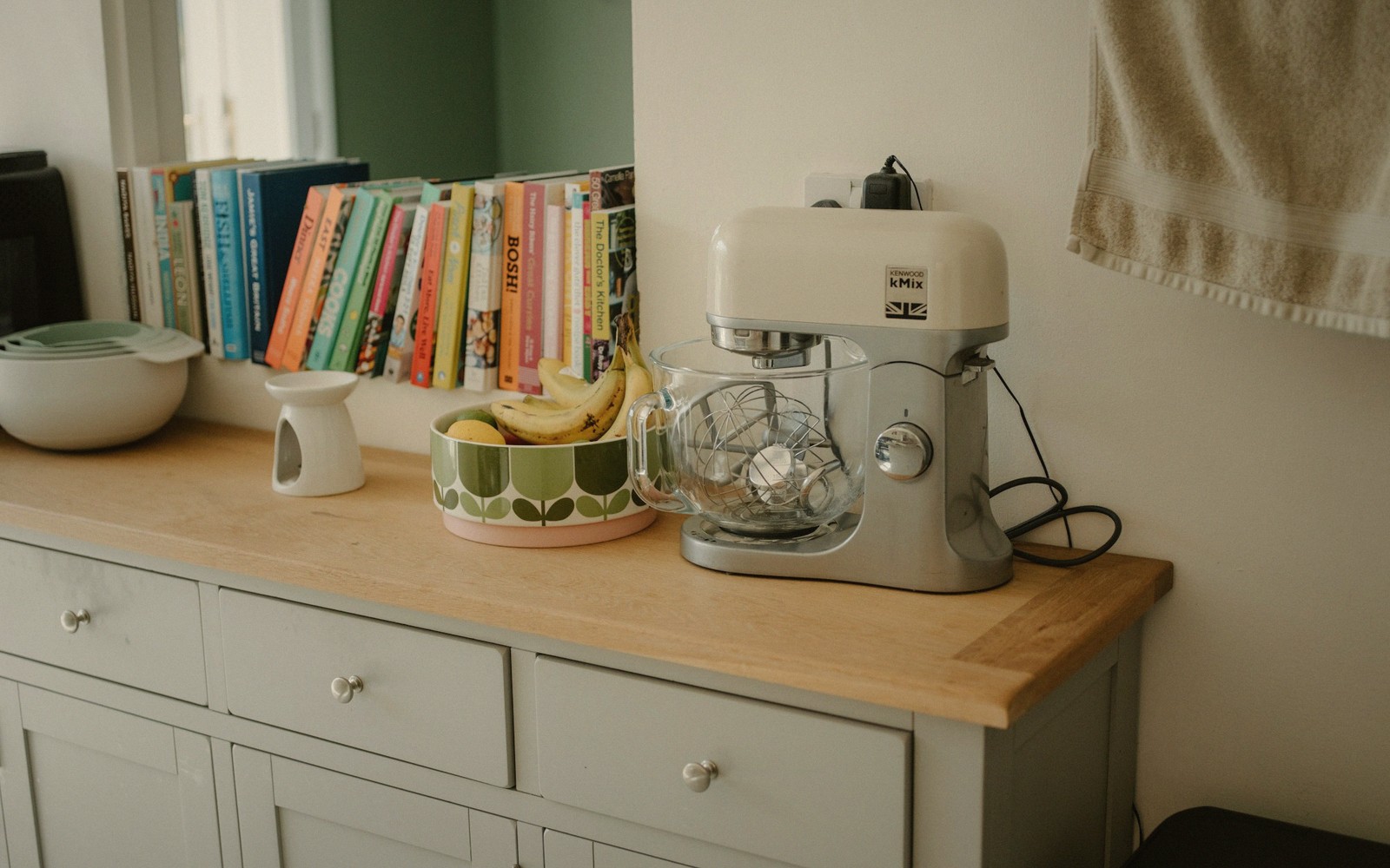 A blender and a bowl of bananas on a sunny kitchen counter