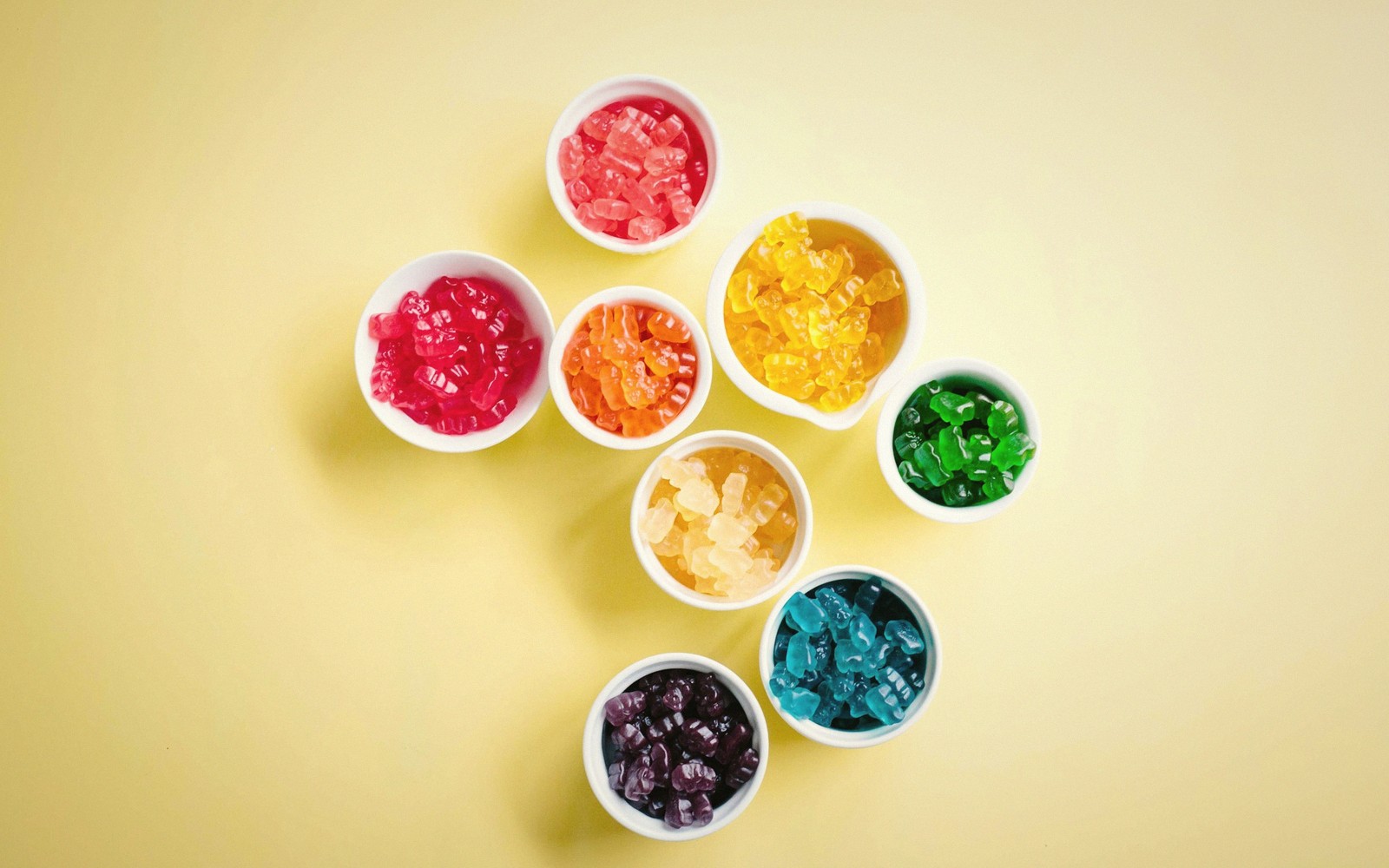 Small bowls of gummy bears in assorted colors arranged in a circular pattern